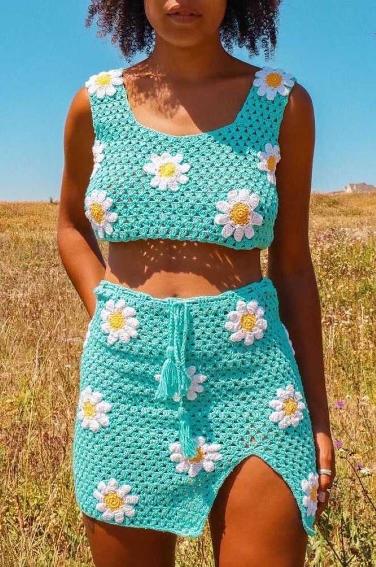 a woman standing in a field wearing a crop top and flowered skirt with high waist