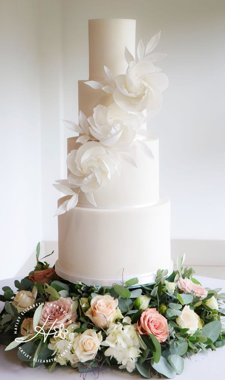 a white wedding cake with flowers and greenery