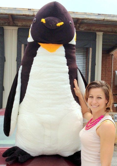 a woman standing next to a large penguin mascot