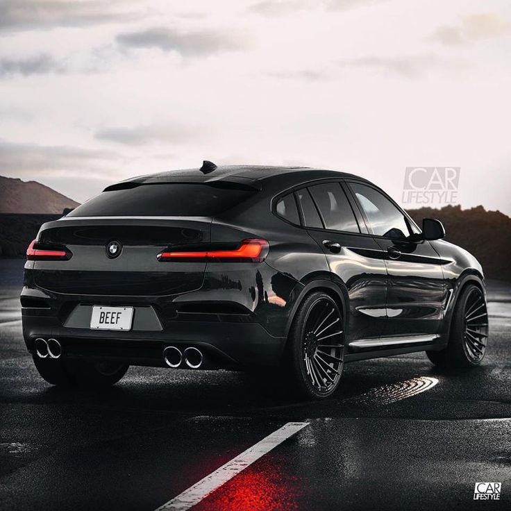 a black bmw suv parked in the rain