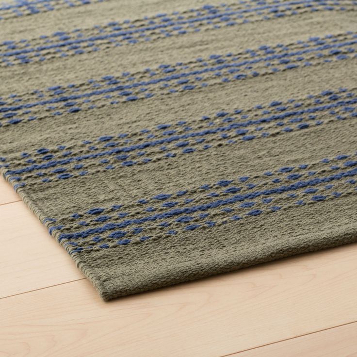 a gray rug with blue and grey squares on it, sitting on a wooden floor