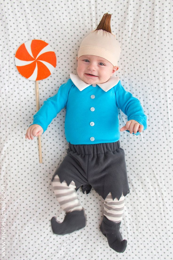 a baby laying on top of a bed next to a lollipop pinwheel