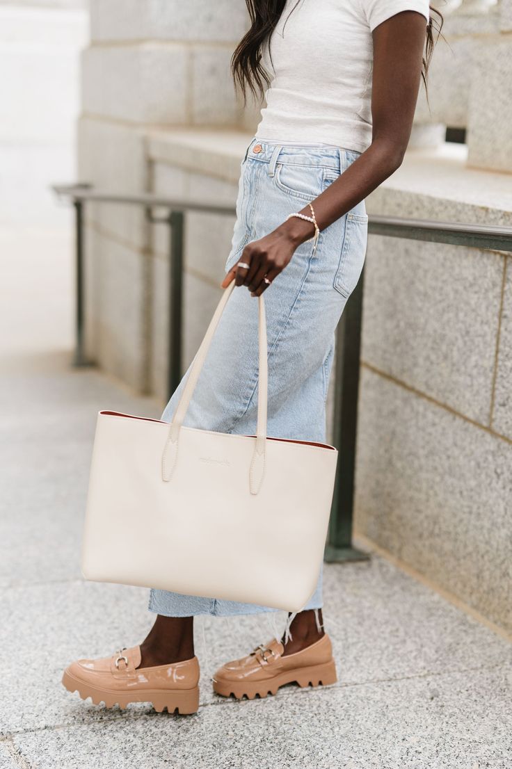 A timeless staple, the Charlotte Tote is sure to become your new on-the-go companion. This spacious shoulder bag is made from sleek, durable vegan leather and is built to fit everything you need for a busy day. Stow your laptop (up to 15"!), wallet, cosmetic bag, and more in this carryall tote. Details: 16" long x 12" height x 6" wide 10" strap drop Snap closure Smooth, silky vegan leather Stamped modern+chic logo Chic Beige Laptop Bag For Travel, Classic Beige Tote Laptop Bag, Chic Beige Laptop Bag, Chic Everyday Laptop Bag With Removable Pouch, Chic Soft Leather Shoulder Laptop Bag, Chic Soft Leather Laptop Shoulder Bag, Chic Laptop Bag With Removable Pouch For On-the-go, Chic Everyday Laptop Bag With Adjustable Strap, Chic Beige Shoulder Laptop Bag