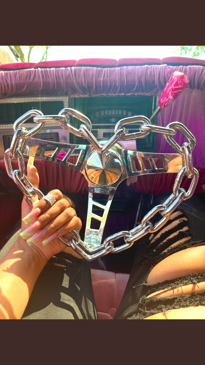 a woman holding up a heart shaped object in front of her face with chains attached to it