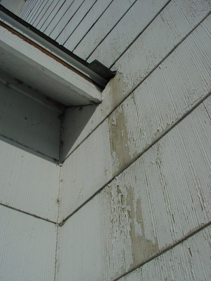 the corner of a white house with a window and gutter on it's side