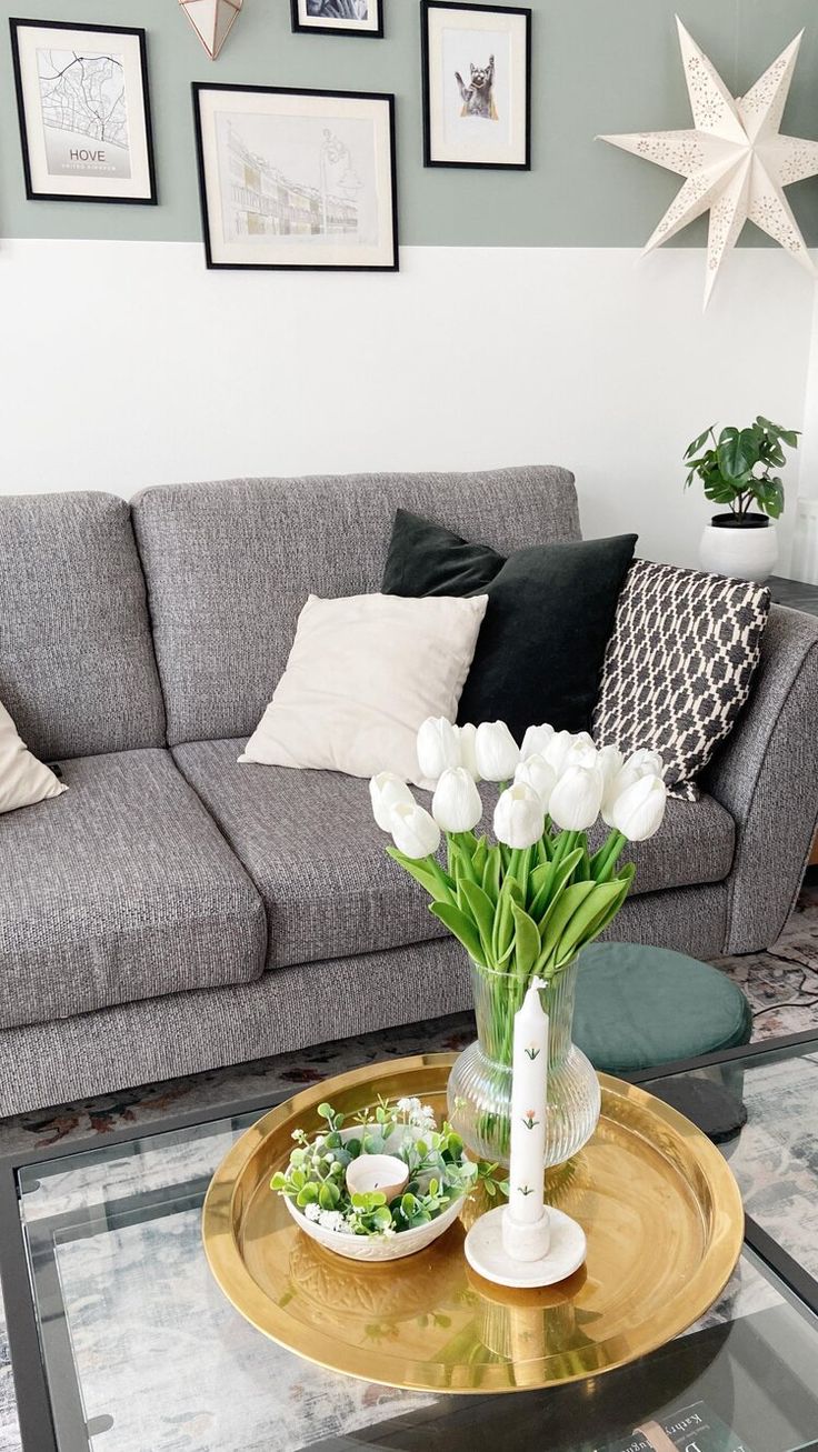 a living room filled with furniture and flowers on top of a coffee table in front of a gray couch