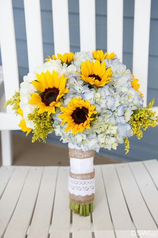 a bouquet of sunflowers and hydrangeas in a vase on a chair