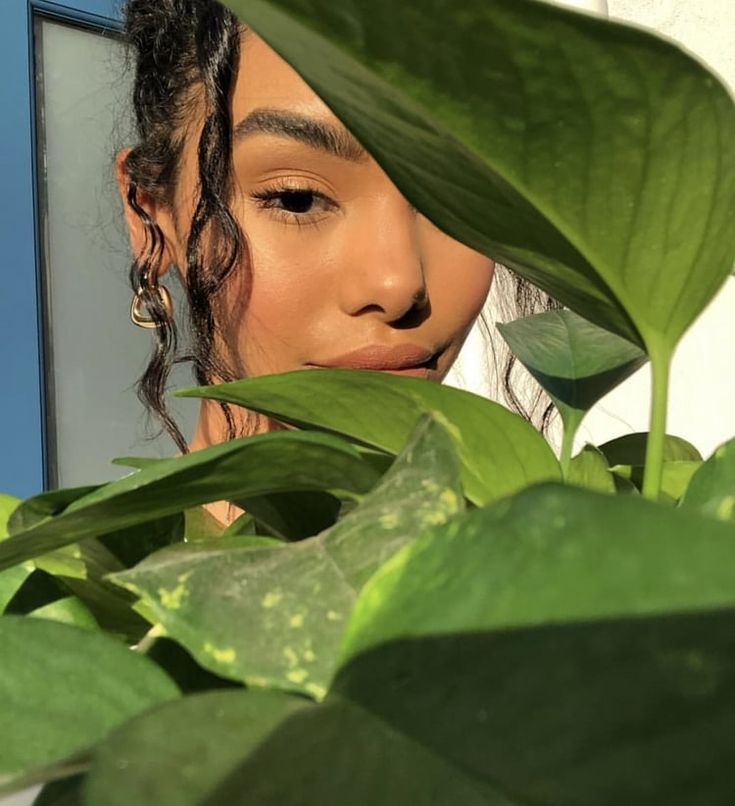 a close up of a person behind some leaves