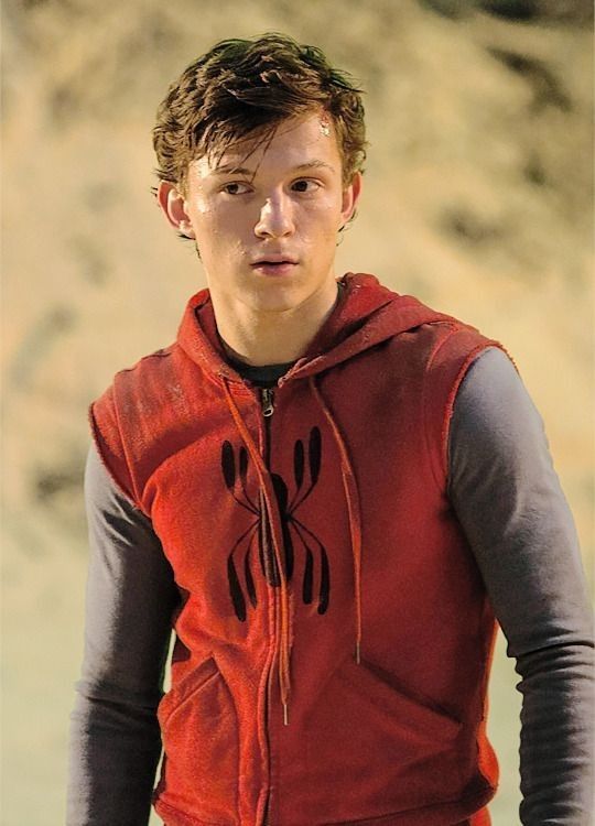 a young man in a red hoodie holding a white frisbee and looking at the camera