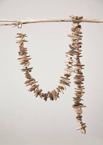 two necklaces made out of driftwood hanging from a branch