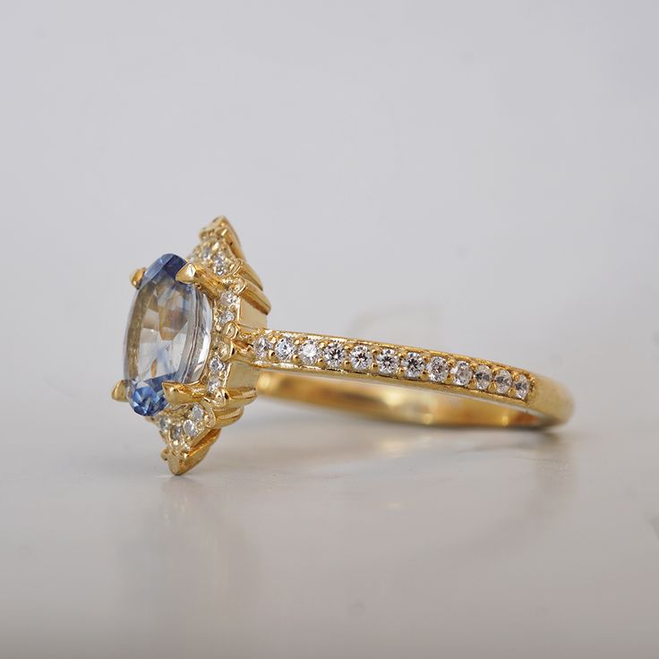 an engagement ring with a blue and white diamond in the center on a plain surface