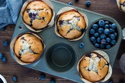 muffins with blueberries in them sitting on a tray