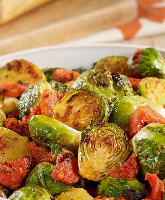 a white bowl filled with brussel sprouts and tomatoes