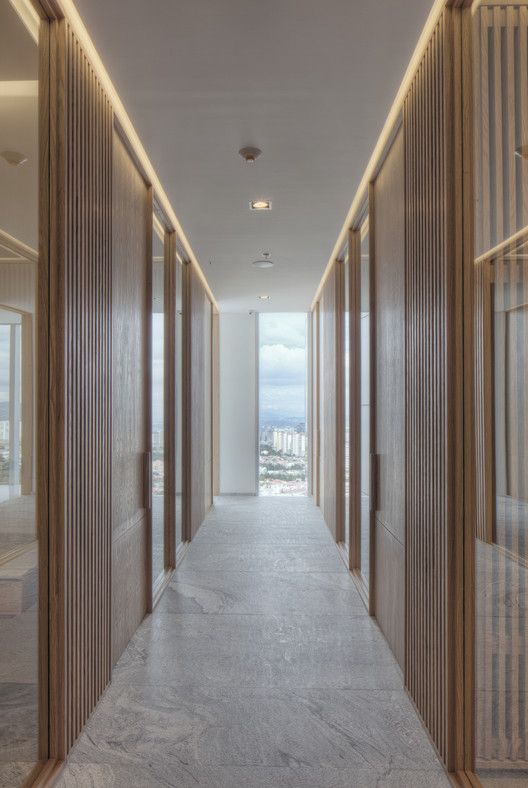 an empty hallway with wooden doors leading to another room and the city in the distance