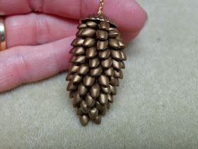 a person is holding a gold pine cone charm