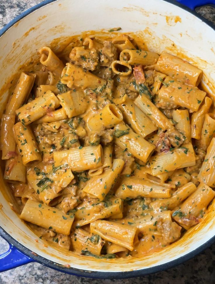 a blue pot filled with pasta covered in sauce