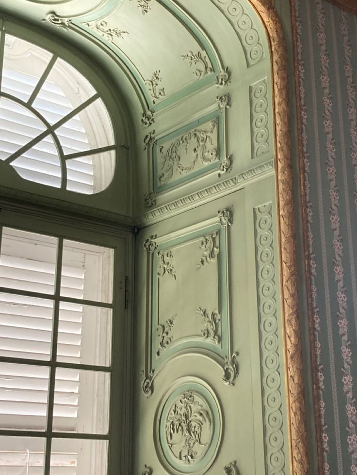 an ornate green door and window in a room with striped wall paper on the walls