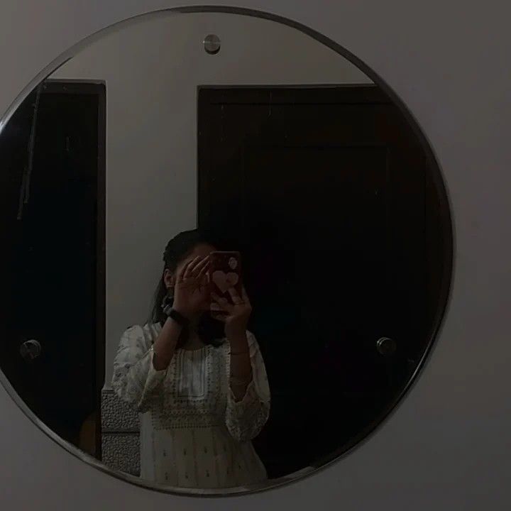 a woman taking a selfie in front of a mirror with her hands on her face