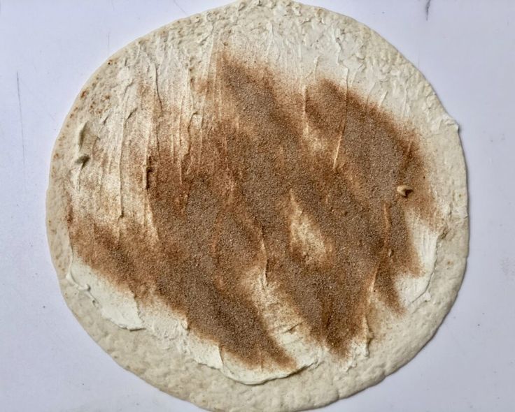 an uncooked tortilla on a white surface with some brown stuff in the middle