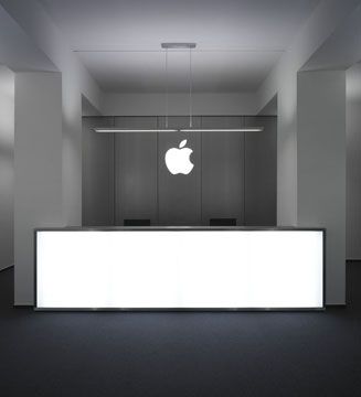 an apple logo is displayed on the wall in front of a white counter and black floor