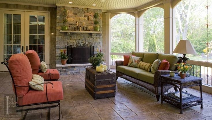 an outdoor living room with couches, tables and chairs on the patio area that is covered in stone