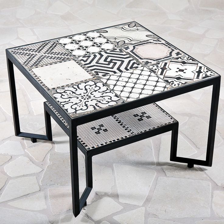 the table is made out of tiles and has black metal legs, which are decorated with different designs