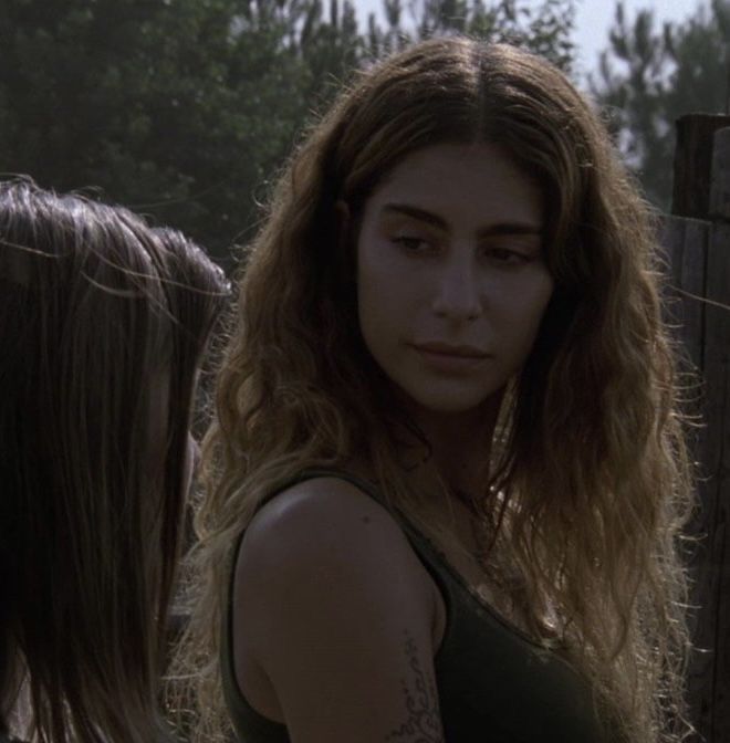 a woman with long hair standing in front of a fence