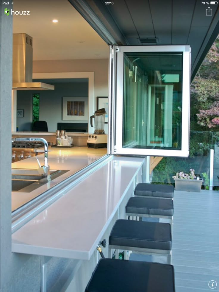 an outdoor kitchen with stainless steel counter tops and stools next to the bar area