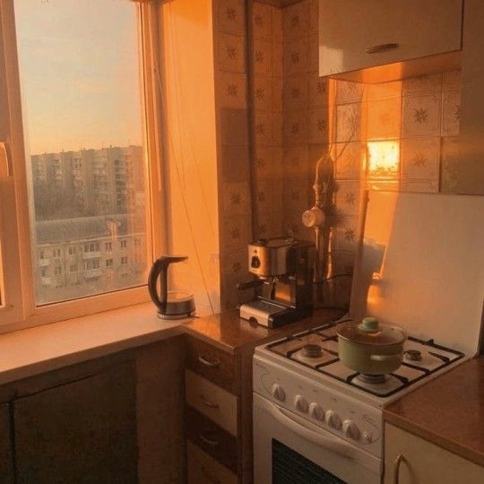 a kitchen with a stove top oven sitting next to a window overlooking a cityscape