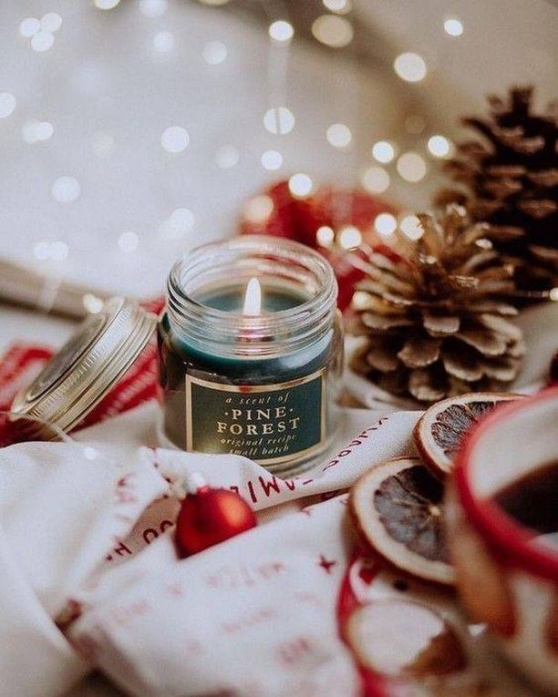 a candle sitting on top of a table next to some christmas decorations and pine cones