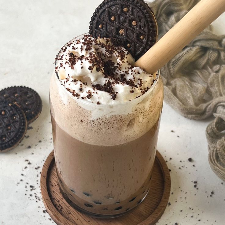 there is a chocolate drink with whipped cream and oreo cookies on the side