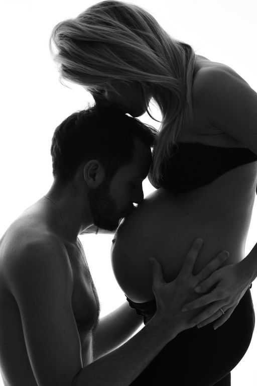 black and white photo of a man kissing a woman's breast in front of a white background