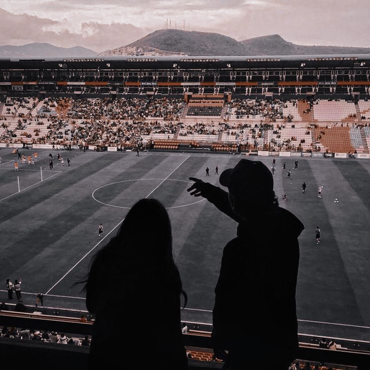 two people standing in front of a soccer field