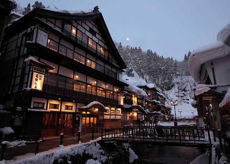 a snow covered mountain side town at night with lights on and buildings in the foreground