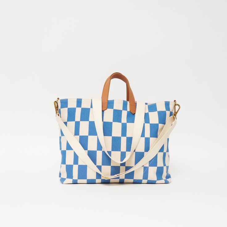 Our new take on Checkers! Our Chambray Checker is our favorite print for our best-selling bag styles. Designed to Carryall. Our mid-size option in our MATATU Collection, the Carryall is your ideal travel companion. Constructed in a sturdy cotton canvas, this bag offers durability, versatility, and reliability. The zip-secure spacious main compartment keeps everything in and features an internal zip compartment for organization along with a quick-access external pocket for on-the-go essentials. F Mother's Day Gift Card, Bag Styles, Spring Bracelet, Clutch Pouch, Mid Size, Backpack Straps, Carry All Bag, Small Wallet, Dog Collars