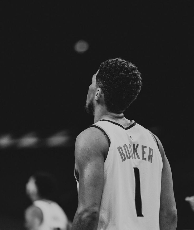 a black and white photo of a man in a basketball uniform looking up at the sky