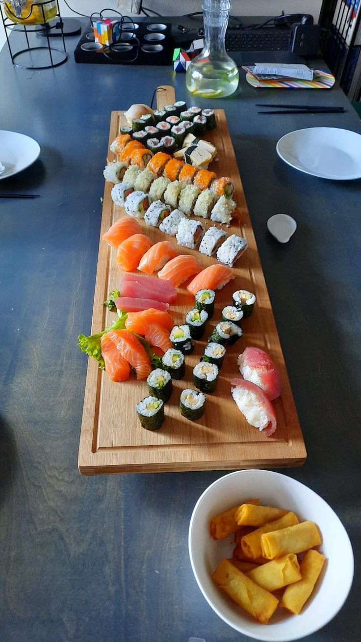 a wooden table topped with plates and bowls filled with sushi on top of it