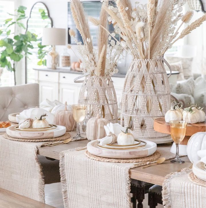 the table is set with white pumpkins, wheat stalks and place settings for two