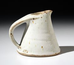 a white pitcher sitting on top of a table next to a black and white background