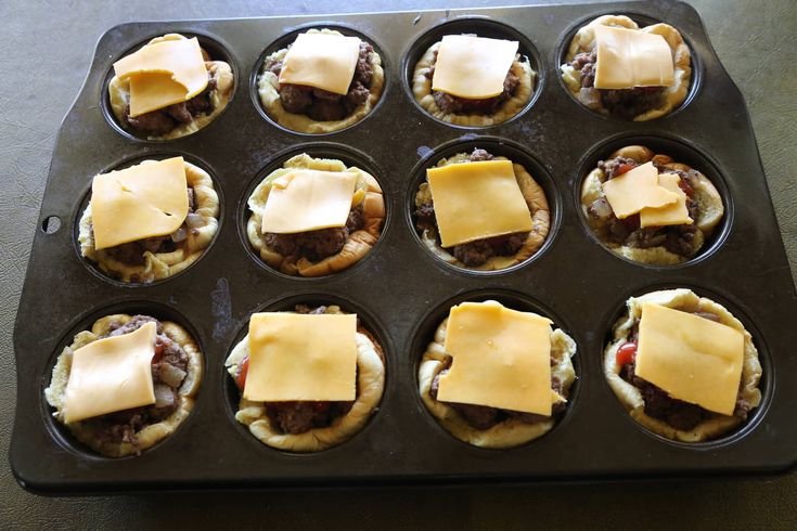 a muffin tin filled with cupcakes topped with cheese and meat patties