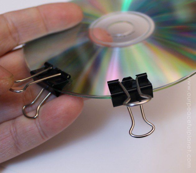 a hand holding a cd with two clips attached to it