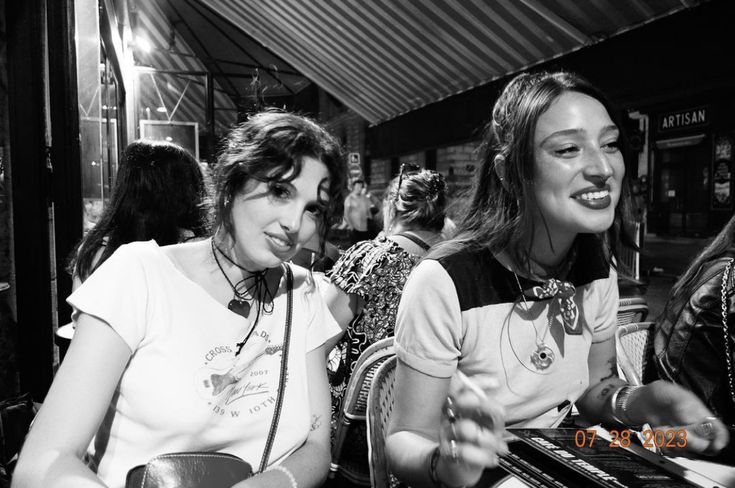 two women sitting next to each other with headphones on and one holding a guitar