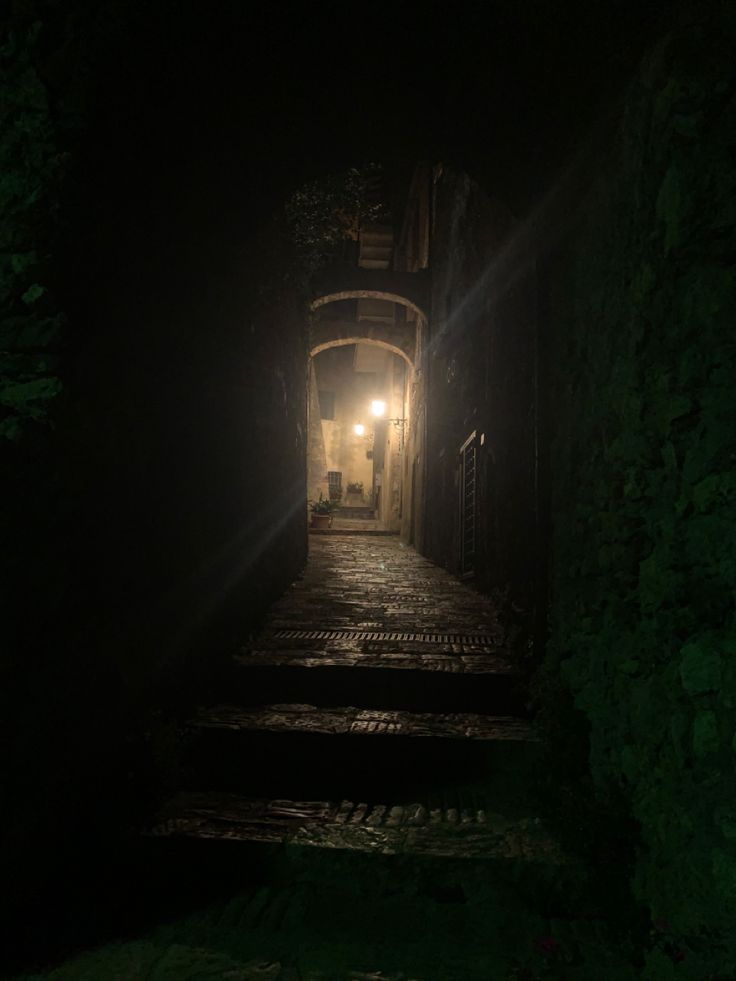 an alley way with steps leading up to a light at the end in the dark