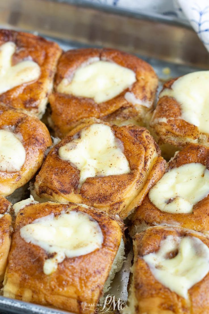 cinnamon rolls with cream cheese on top in a baking pan, ready to be eaten