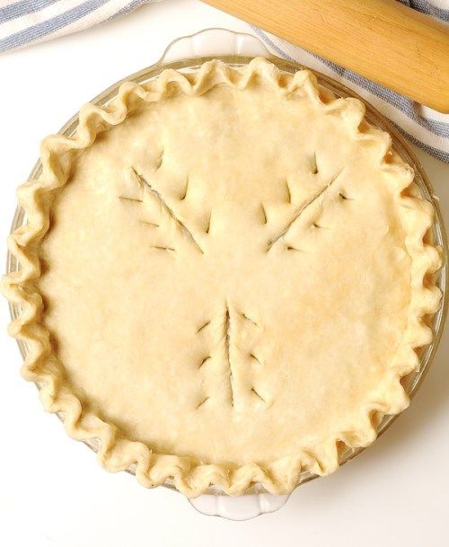 an uncooked pie sitting on top of a table next to a rolling pin