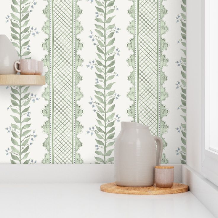 a white vase sitting on top of a counter next to a wallpapered wall