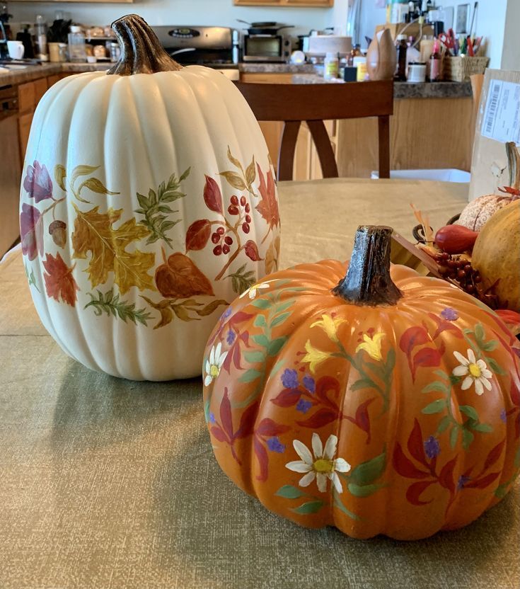 two painted pumpkins sitting on top of a table next to each other in front of a kitchen counter