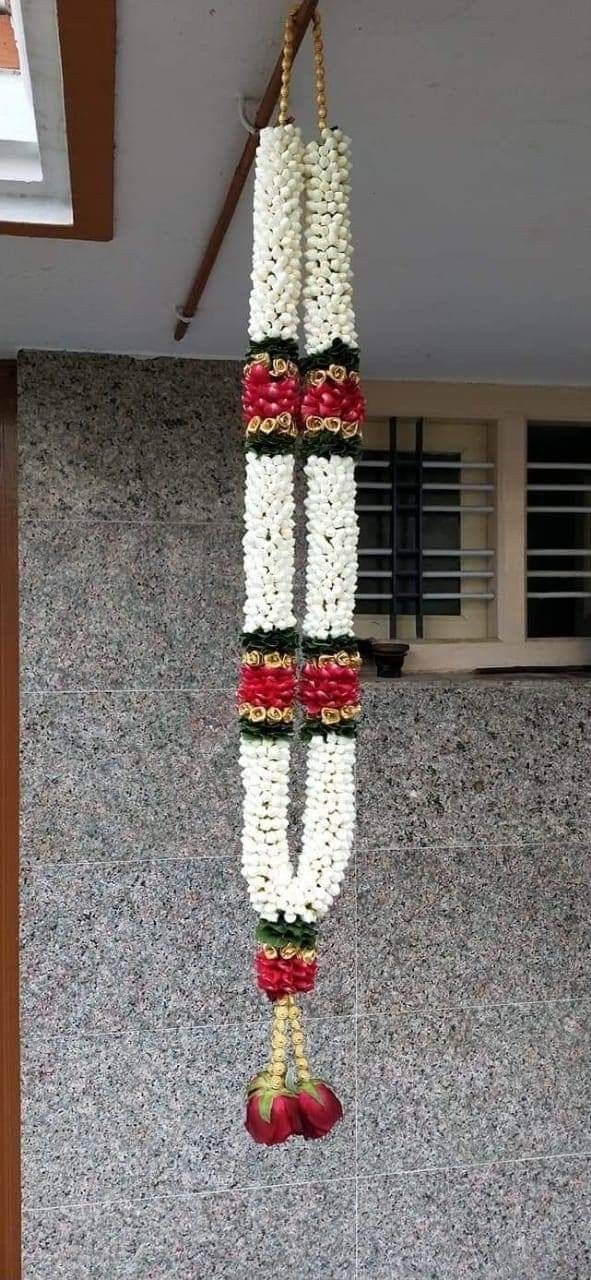 an arrangement of white and red flowers hanging from a rope in front of a building