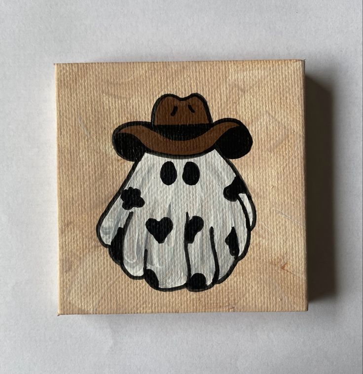 a wooden block with a drawing of a cow wearing a cowboy hat