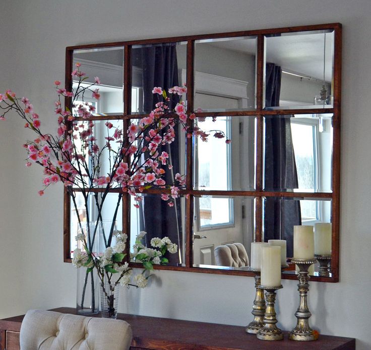 a mirror sitting on top of a wooden table next to a vase with flowers in it